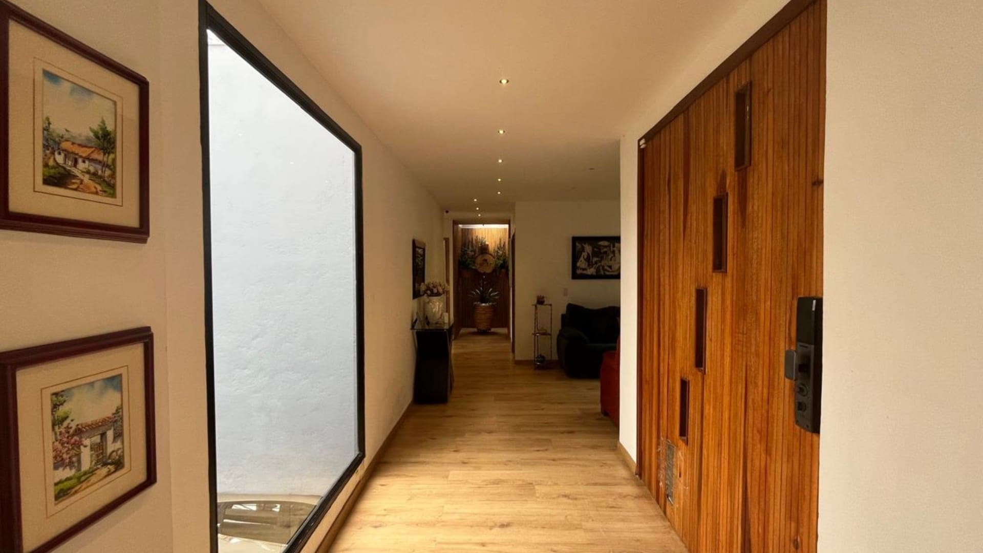 Acceso interior con puerta en madera maciza y piso en madera clara