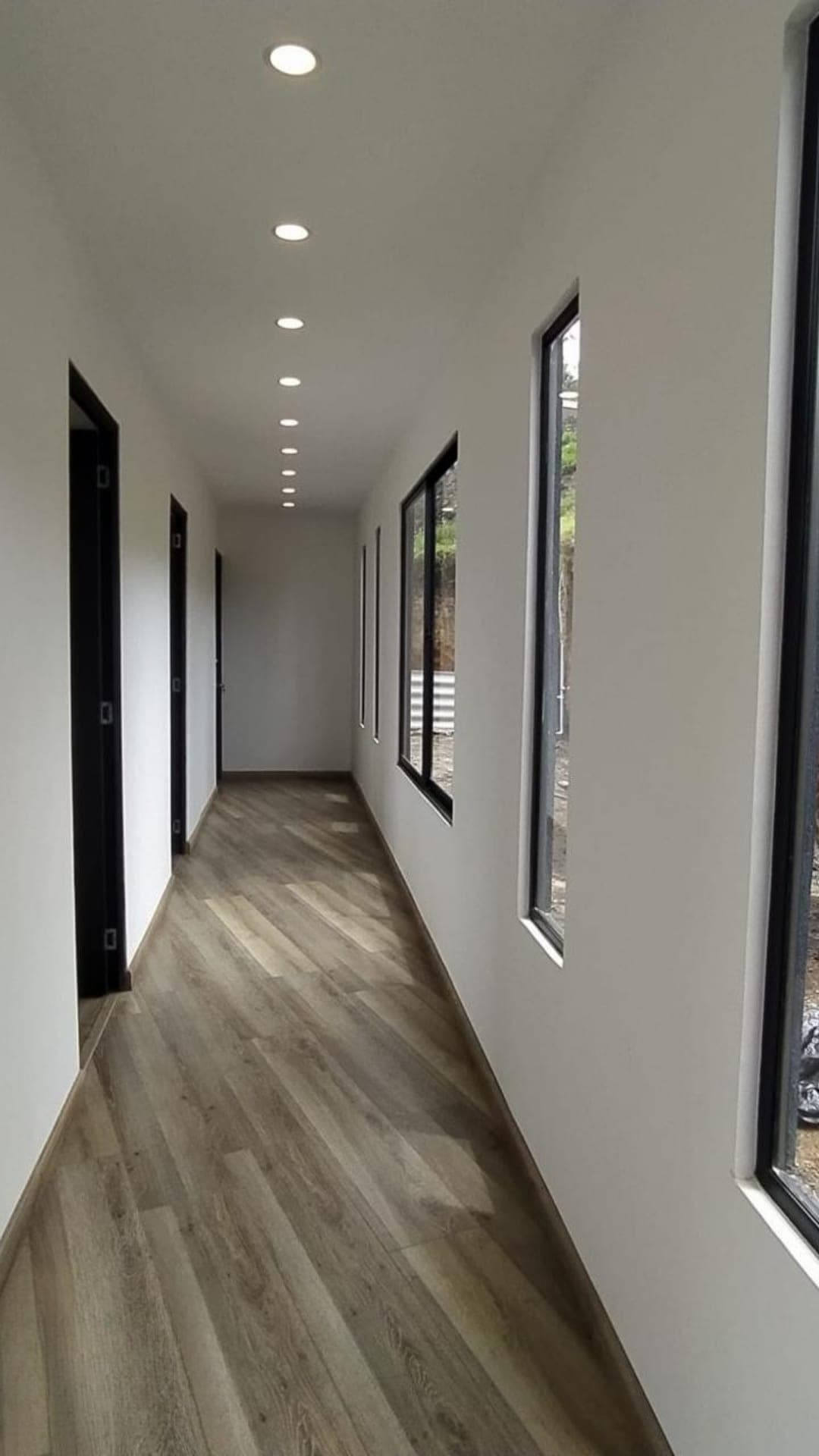 Pasillo con cielo raso e iluminación empotrada y piso símil madera