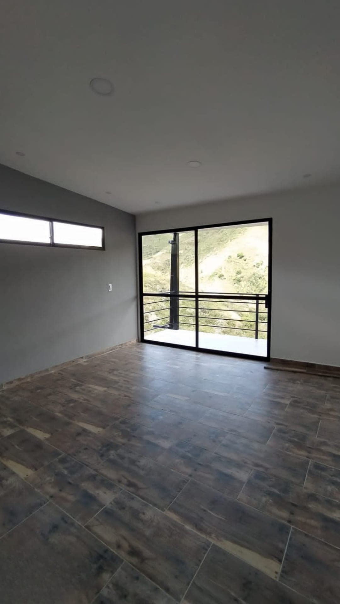 Habitación terminada con ventanal corredizo hacia un balcón con vista a la montaña
